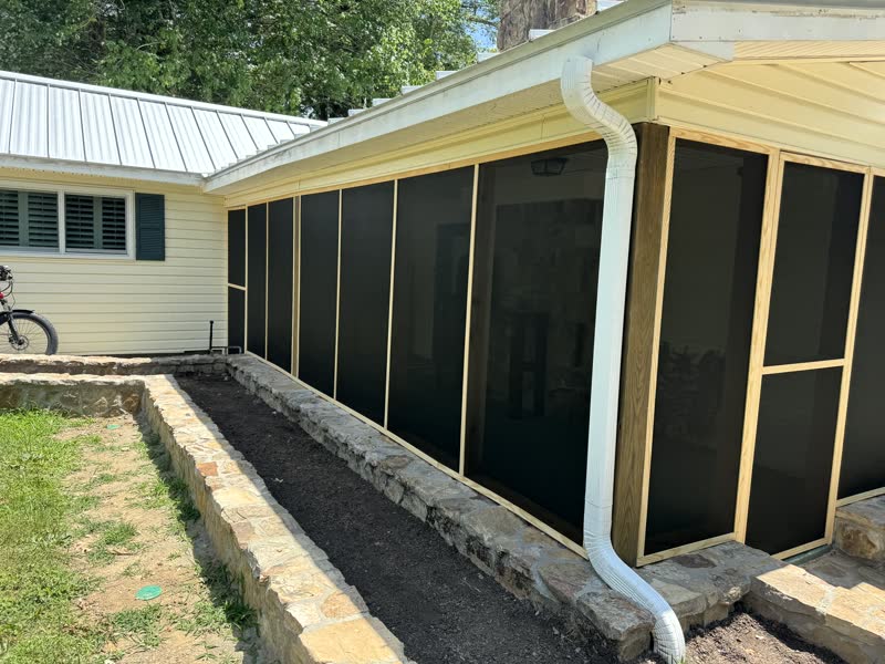 Cedar-framed screened porch addition set on a hand-laid stone retaining wall